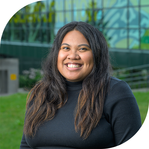 Admissions Counselor Daphne Ang smiling at camera in front of Welcome to UAA kiosk.