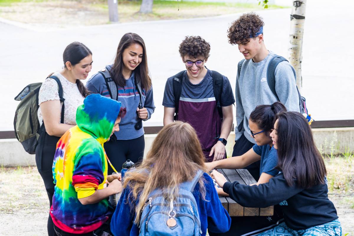 UAF Students gather at a picnic table outside the Wood Center on the Fairbanks Troth Yeddha' campus