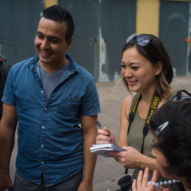 Woman with notebook in her hand laughs with man in group of people.