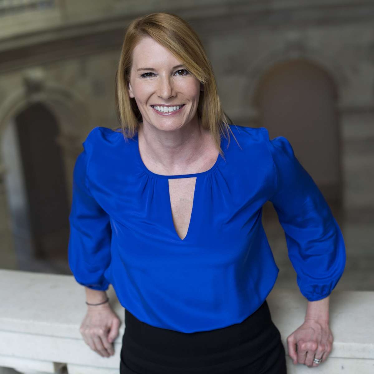 Woman in blue shirt stands in marble building