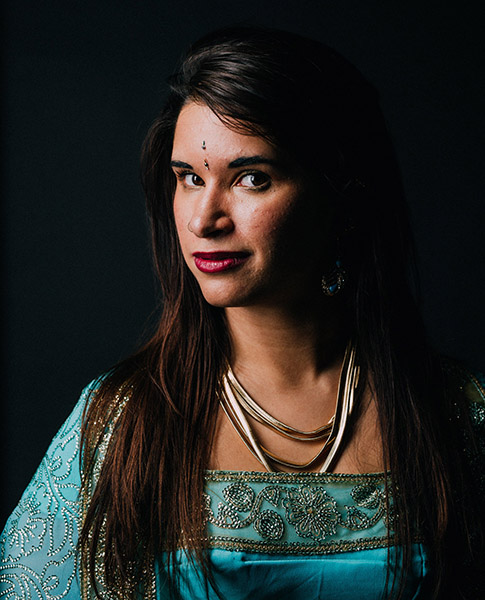 This is a headshot of a dark-haired female with makeup and a blue Eastern outfit 