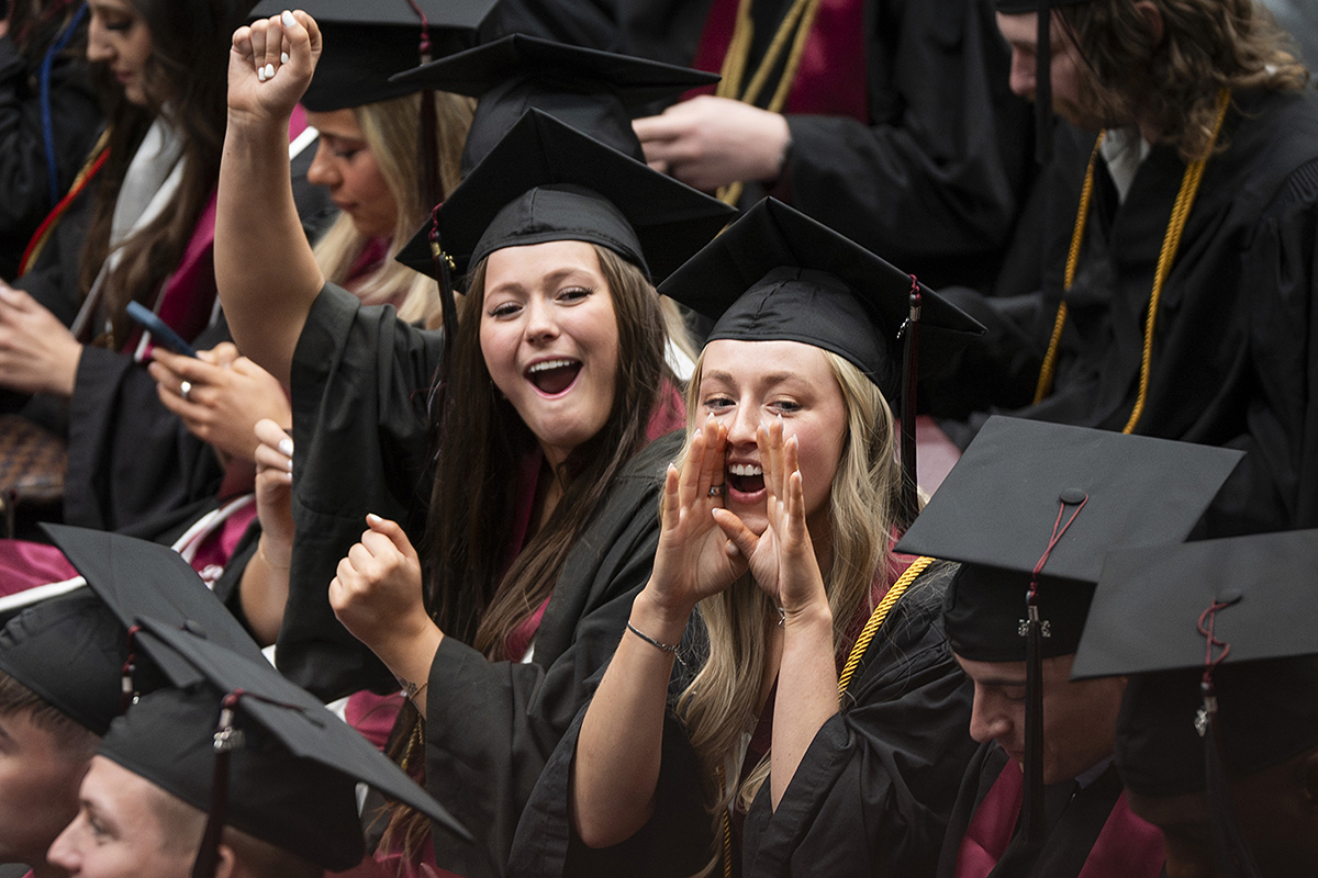 Two female students wave at UM graduation.