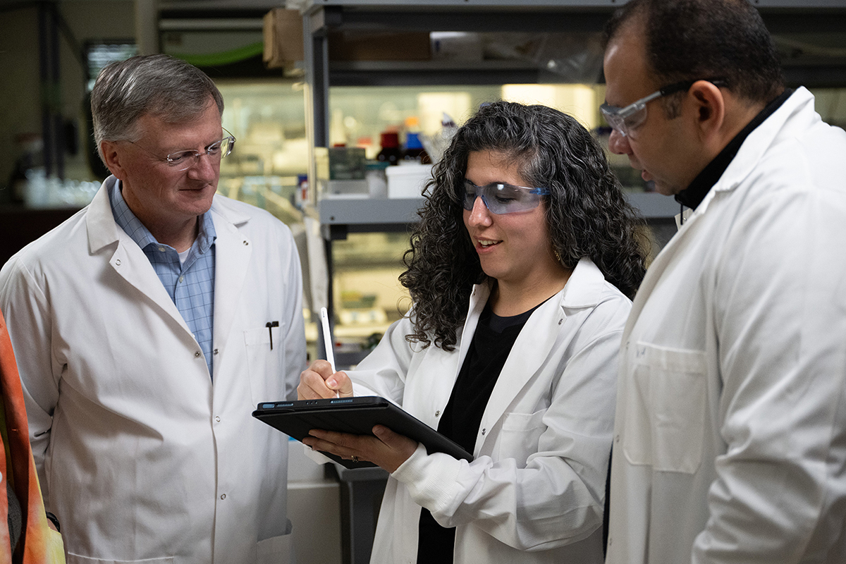 Jay Evans, Asia Riel and Walid Abdelwahab work in a lab.