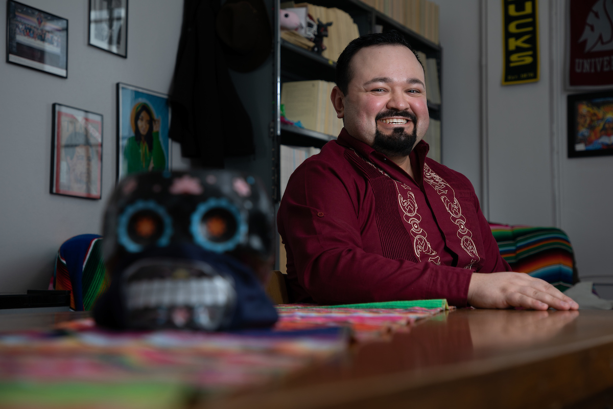 A man sits at a desk and smiles 