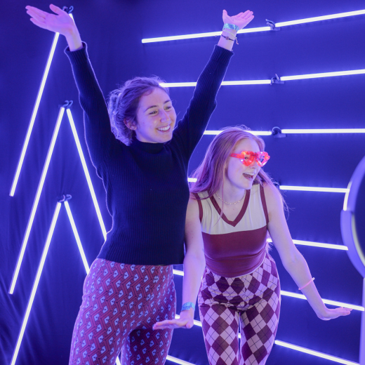 Two students pose for a camera with blue lights surrounding them