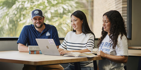 three students in the library studying