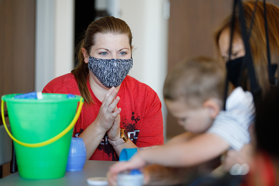 Tonya Hinrichs encourages her son as he grabs building blocks in an occupational therapy session at MMI.