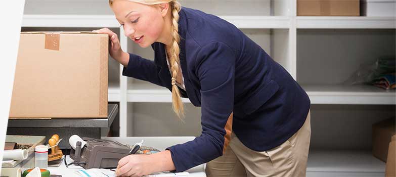 Woman checking shipping box weight and postage.