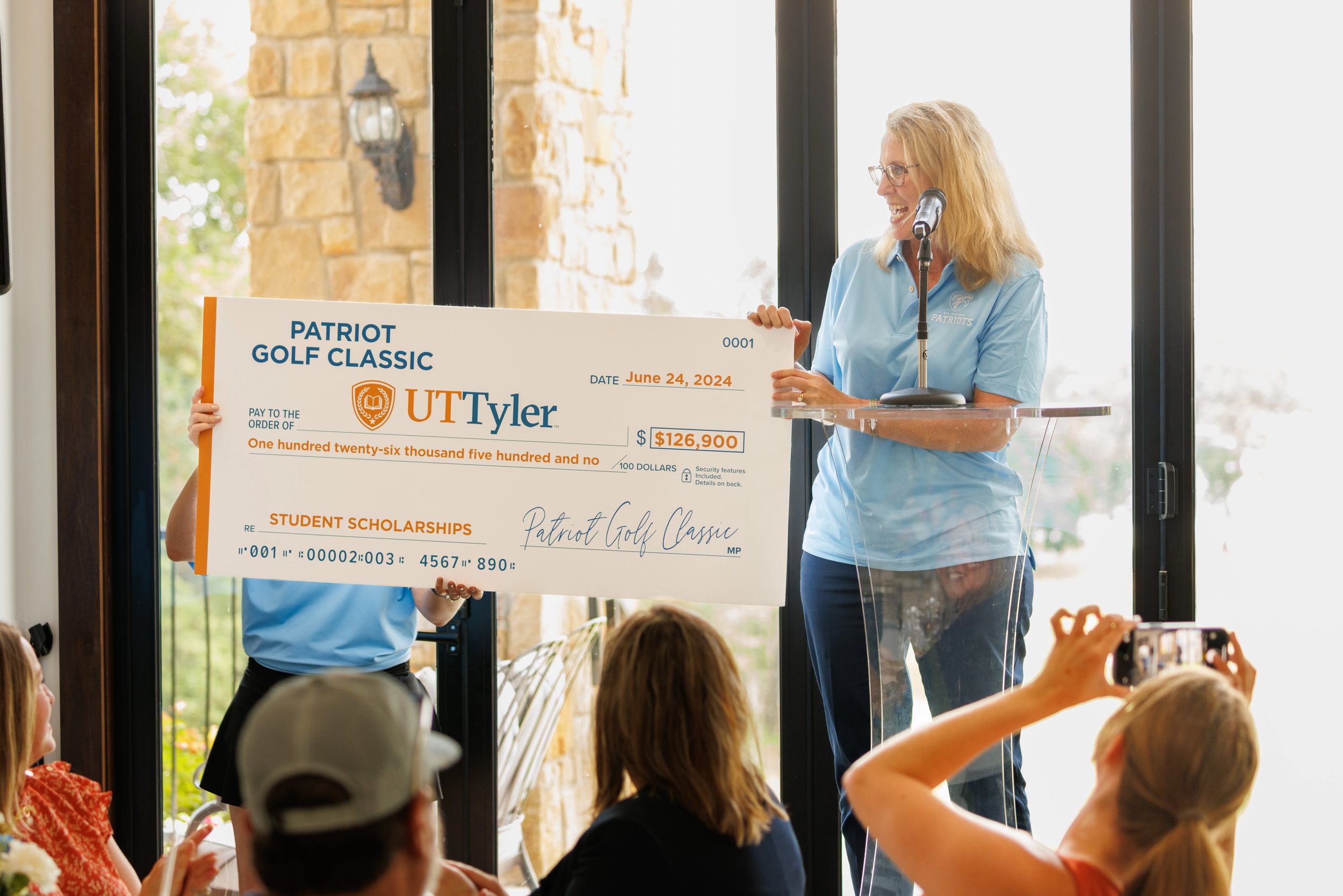 University of Texas at Tyler alumni hold a large check at a fundraising event