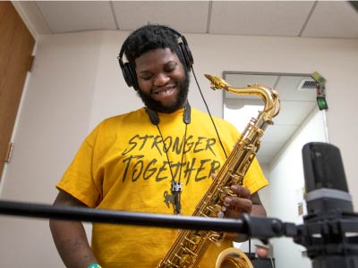 A graduate students records in the studio with his saxophone