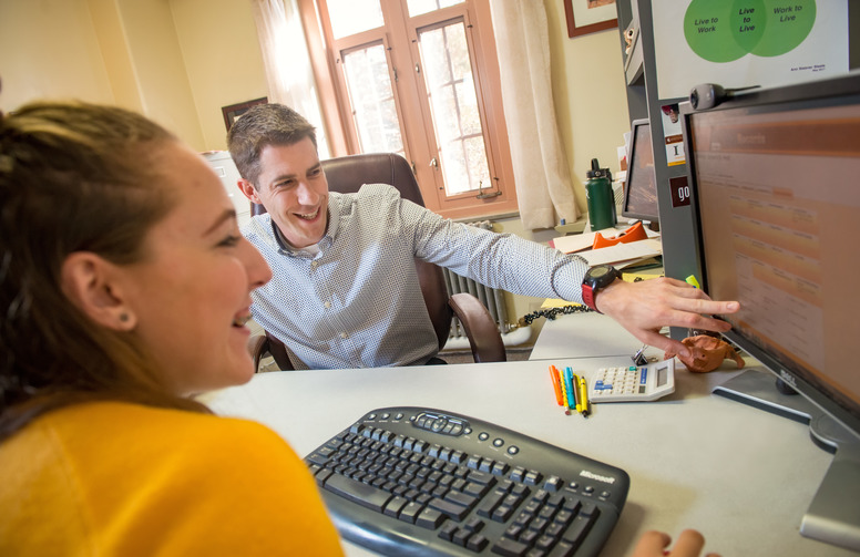 Student and career services advisor looking at a computer monitor.