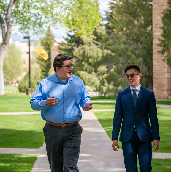 Two people wearing suits walking