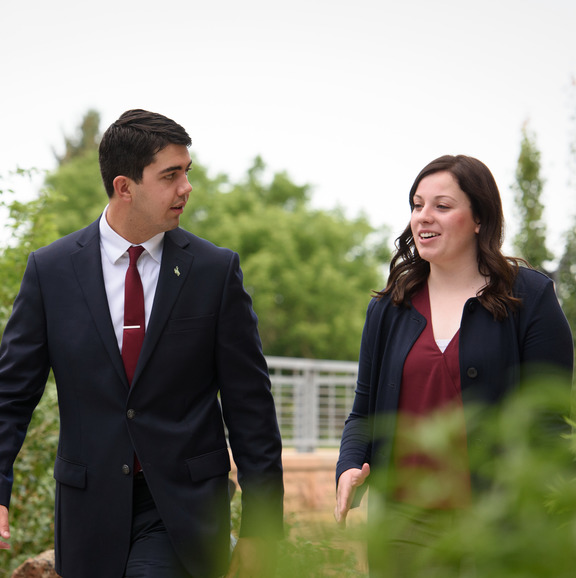 Two people wearing suits walking