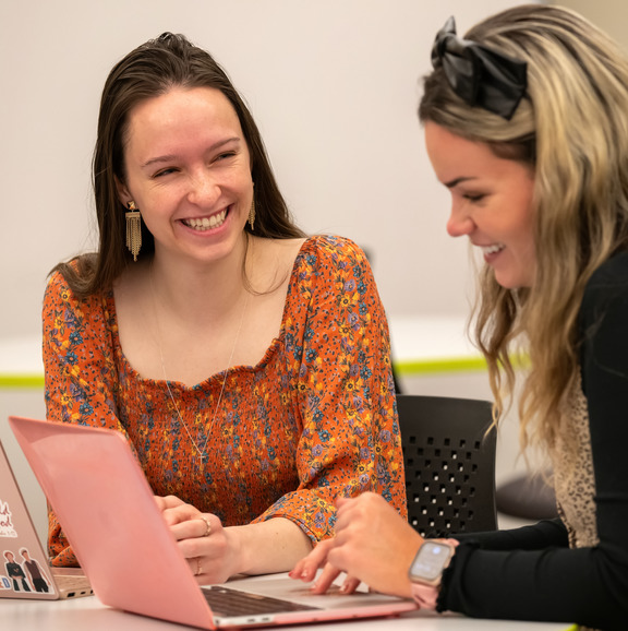 Two people on their computers and laughing