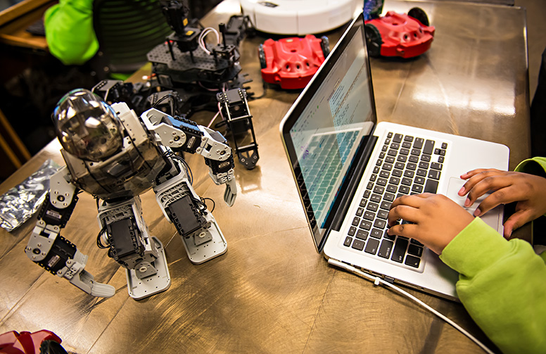 student types on laptop computer as they program robot