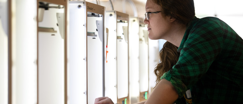 A student looks at several 3D printers inside the CEPS makerspace.