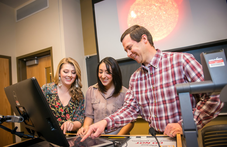 group of people looking at a projection monitor in a classroom