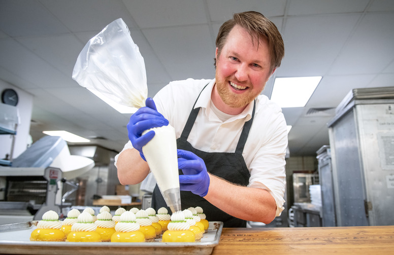 person frosting pastries in an industrial kitchen.