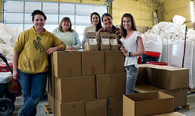 five people with a stack of boxes and many large sacks, with smaller bags on top of the boxes