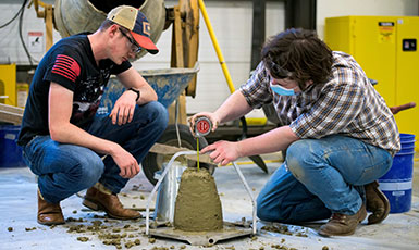 two people pouring something into a concrete shape