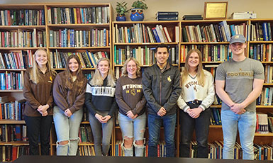 group of people standing in front of bookshelves