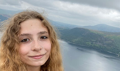 woman standing against a background of mountains and water