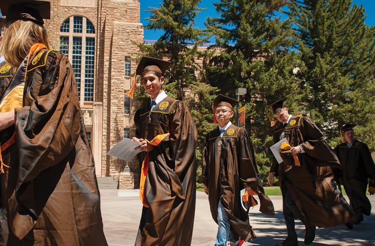 UW students in graduation gowns walking outside 