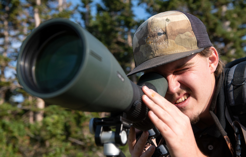 A student looking through a large camera lens in the field