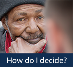 An elderly man of color listening to a staff worker.