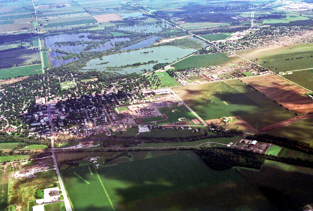 Photo showing damage path of 1990 Plainfield tornado from an airplane. Damage to buildings and vegetation is evident, which creates a clear path from near the foreground to the background. Photo vantage is from just west of Plainfield looking east-southeastward.