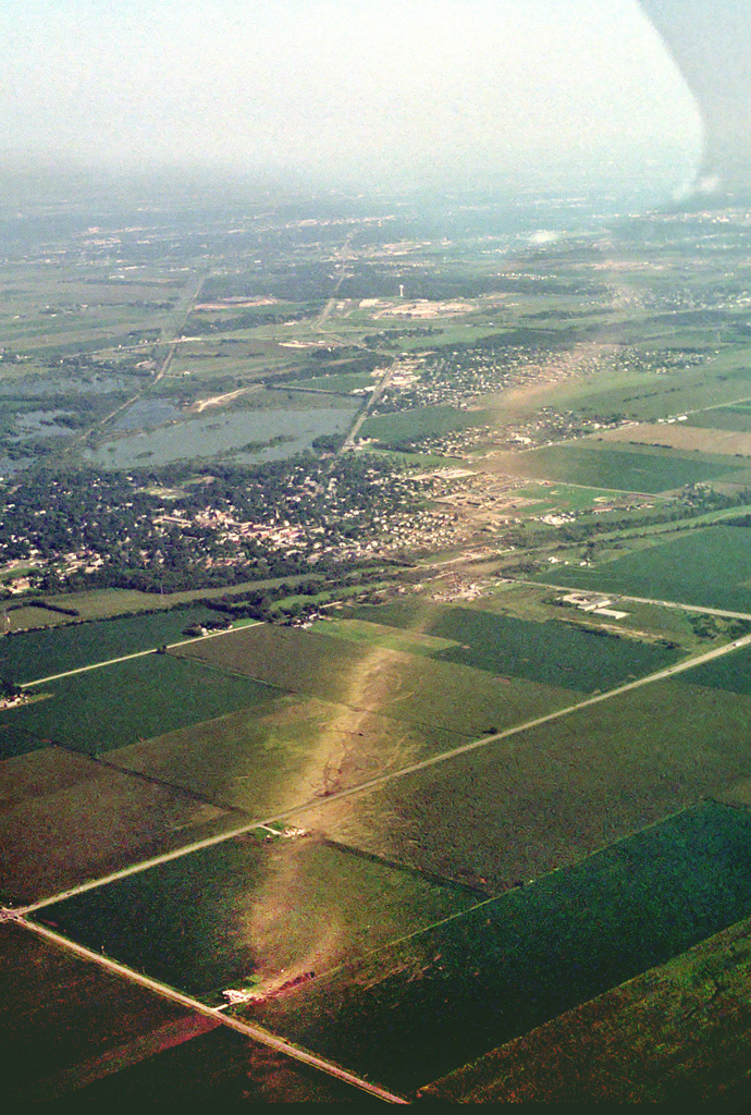 Photo showing damage path of 1990 Plainfield tornado from an airplane. Damage to buildings and vegetation is evident, which creates a clear path from near the foreground to the background. Photo vantage is from near 143rd Street and Wallin Drive northwest of Plainfield looking southeastward.