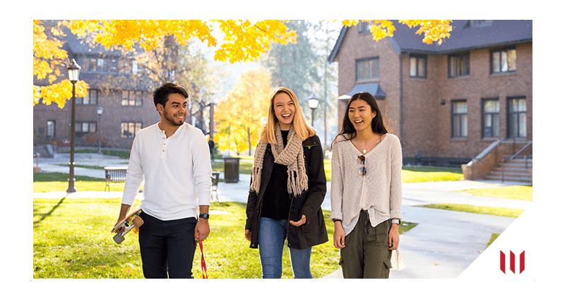 Three students walking on campus path