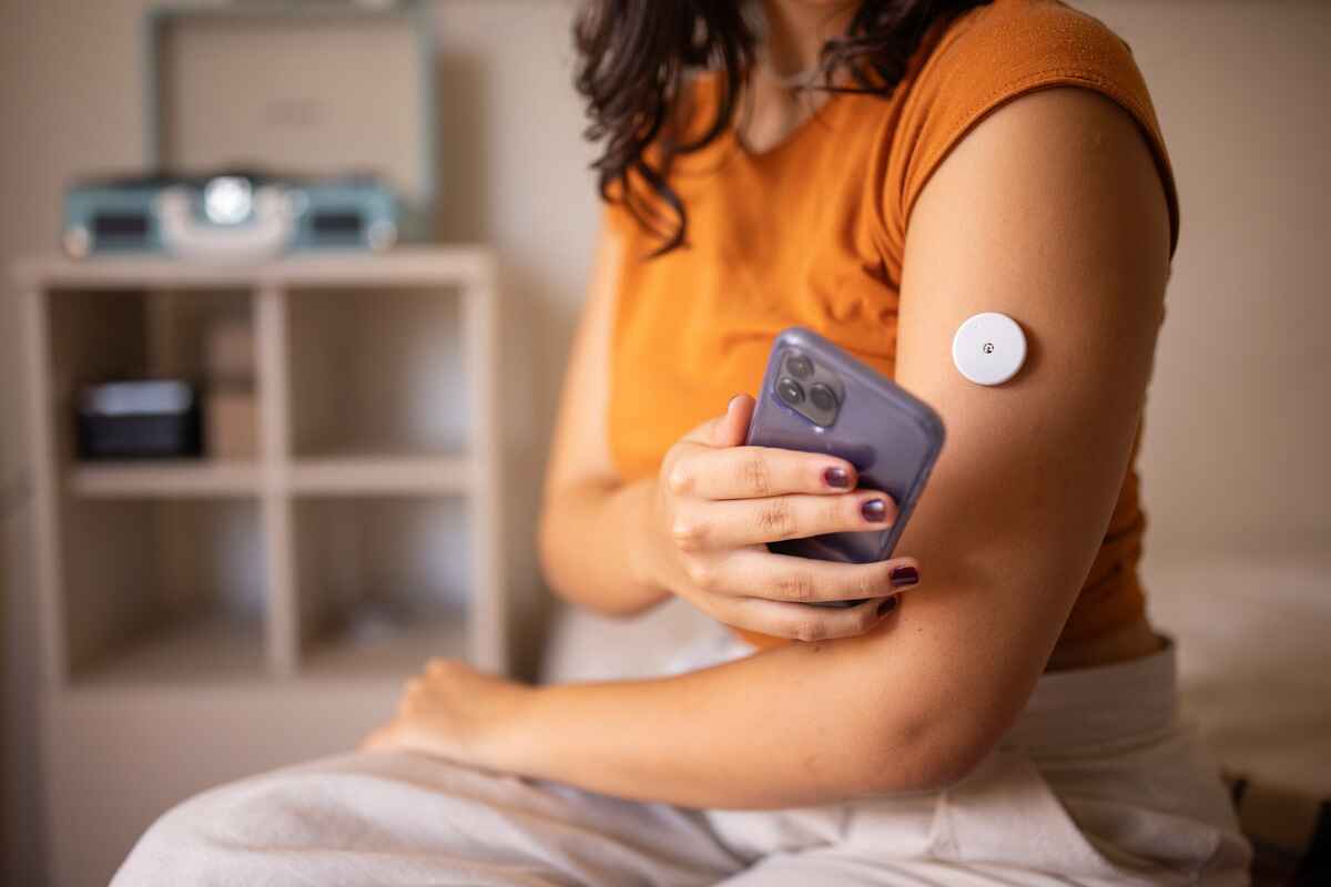 Woman wearing a blood glucose monitor tracks her blood sugar levels