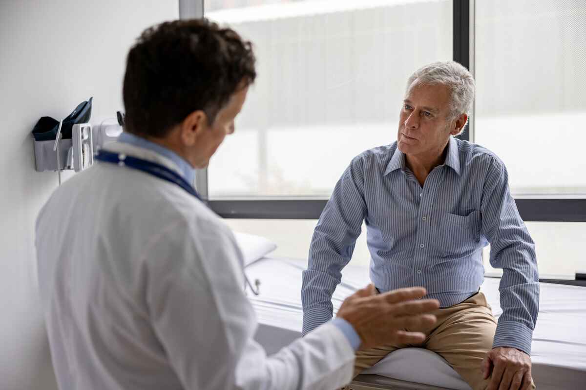 Older man preparing for open heart surgery talks to doctor